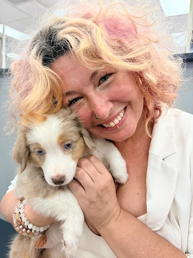 A woman smiling while holding a puppy